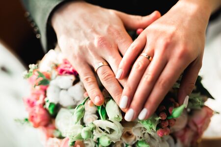 Beautiful young wedding couple posing with bouquet of flowers in handsの写真素材