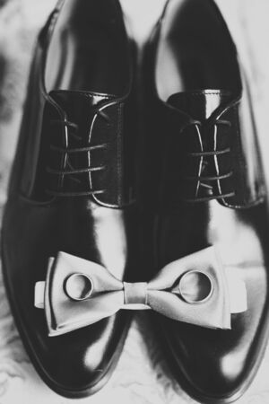 Set of mans fashion shoes with two golden wedding rings.の写真素材