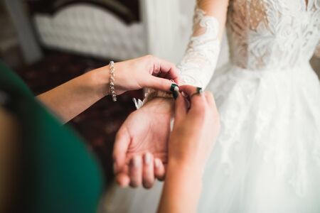 Hands of bridesmaids on bridal dress. Happy marriage and bride at wedding day conceptの写真素材