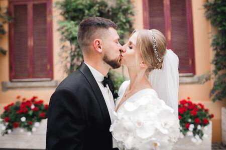 Beautiful bride and groom embracing and kissing on their wedding dayの写真素材