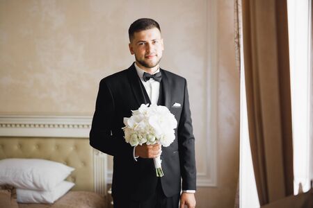 Beautiful man, groom holding big and beautiful wedding bouquet with flowersの写真素材