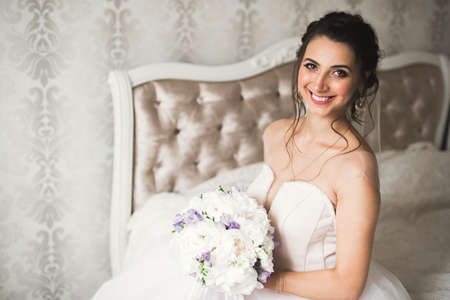 Gorgeous bride in robe posing and preparing for the wedding ceremony face in a room