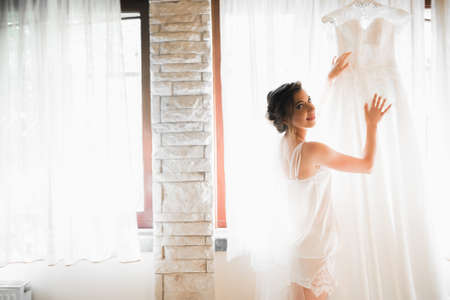 Gorgeous bride in robe posing and preparing for the wedding ceremony face in a roomの写真素材