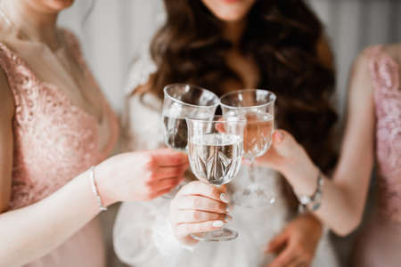 Photo bride with her friends drinking champagne from glassesの写真素材