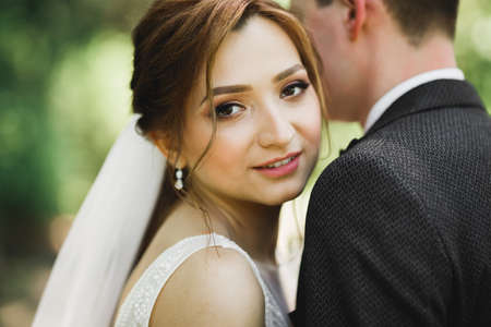 Beautiful romantic wedding couple of newlyweds hugging in parkの写真素材