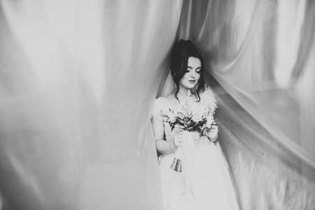 Beautiful bride wearing fashion wedding dress with feathers with luxury delight make-up and hairstyle, studio indoor photo shootの写真素材