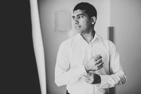 Grooms morning preparation. Handsome man getting dressed and preparing for the weddingの写真素材