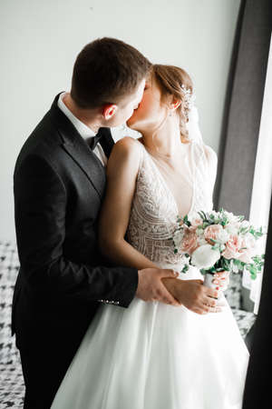 Beautiful bride and groom embracing and kissing on their wedding dayの写真素材