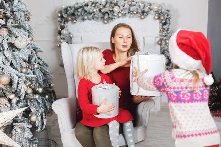 Mother and her daughters opening the little girls birthday presentの写真素材