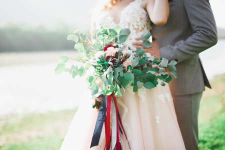 Emotional beautiful bride hugging newlywed groom at a field closeupの写真素材
