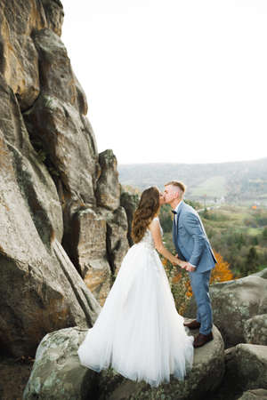 Beautiful bride and groom embracing and kissing on their wedding day outdoorsの写真素材