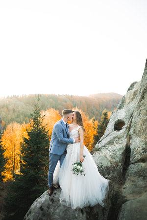 Beautiful bride and groom embracing and kissing on their wedding day outdoorsの写真素材