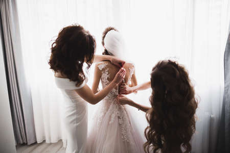 Hands of bridesmaids on bridal dress. Happy marriage and bride at wedding day conceptの写真素材
