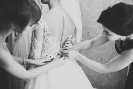 Hands of bridesmaids on bridal dress. Happy marriage and bride at wedding day conceptの写真素材
