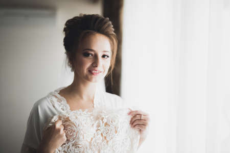 Beautiful bride wearing fashion wedding dress with feathers with luxury delight make-up and hairstyle, studio indoor photo shootの写真素材