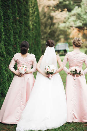 Bride with bridesmaids holding wonderful luxury wedding bouquet of different flowers on the wedding dayの写真素材