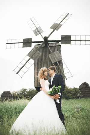 Emotional beautiful bride hugging newlywed groom at a field closeupの写真素材