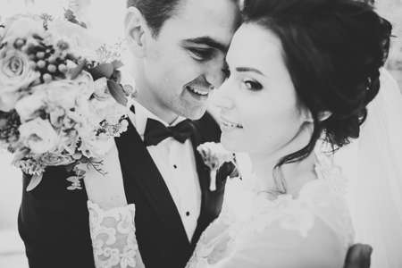 Romantic, fairytale, happy newlywed couple hugging and kissing in a park, trees in backgroundの写真素材