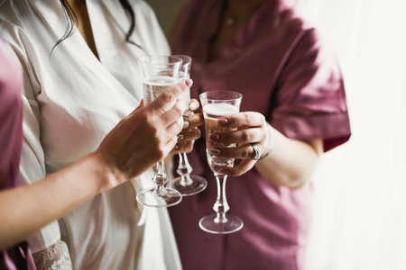 Photo bride with her friends drinking champagne from glassesの写真素材