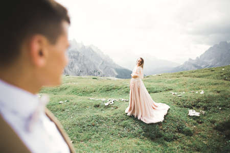 Beautiful gorgeous bride posing to groom and having fun near at mountains with amazing view, space for text, wedding coupleの写真素材