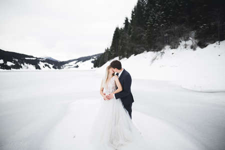 Young happy couple kissing, mountains landscape in snow on the backgroundの写真素材
