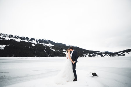 Young happy couple kissing, mountains landscape in snow on the backgroundの写真素材