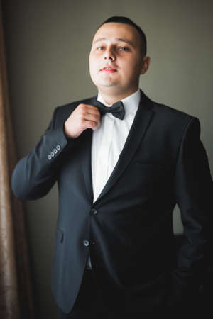 Grooms morning preparation. Handsome man getting dressed and preparing for the weddingの写真素材