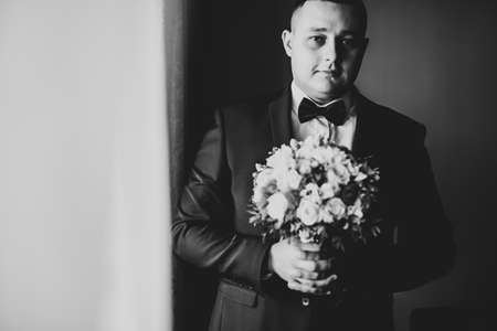 Grooms morning preparation. Handsome man getting dressed and preparing for the weddingの写真素材