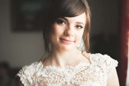 Gorgeous bride in robe posing and preparing for the wedding ceremony face in a room