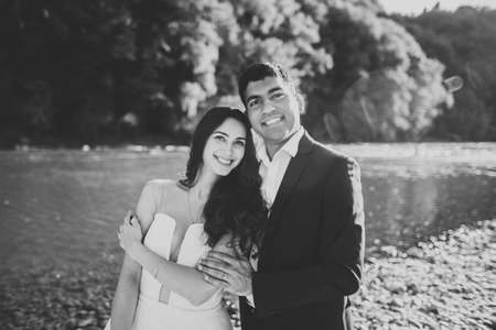 Wedding couple, groom and bride hugging, outdoor near riverの写真素材