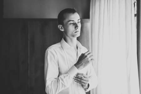 Grooms morning preparation. Handsome man getting dressed and preparing for the weddingの写真素材