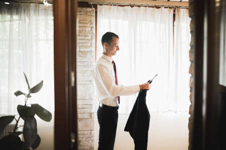 Grooms morning preparation. Handsome man getting dressed and preparing for the weddingの写真素材