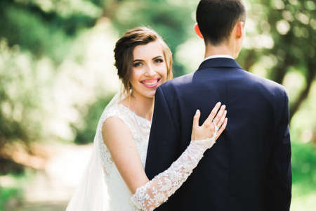Beautiful romantic wedding couple of newlyweds hugging in parkの写真素材