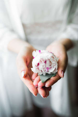 Beautiful luxury bride in elegant white dress holds bouquet of flowers in the handsの写真素材