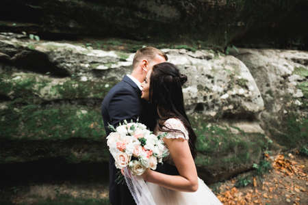 Beautiful gorgeous bride posing to groom and having fun near at mountains with amazing view, space for text, wedding couple.の写真素材