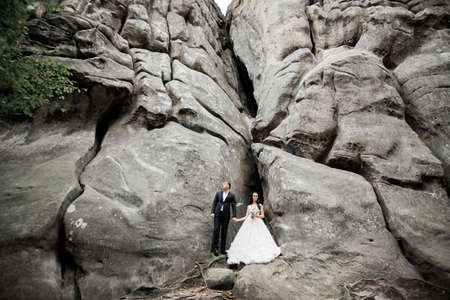 Beautiful gorgeous bride posing to groom and having fun near at mountains with amazing view, space for text, wedding coupleの写真素材