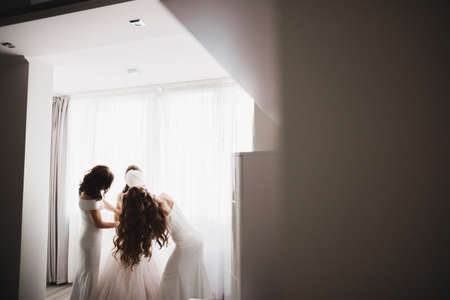 Hands of bridesmaids on bridal dress. Happy marriage and bride at wedding day conceptの写真素材