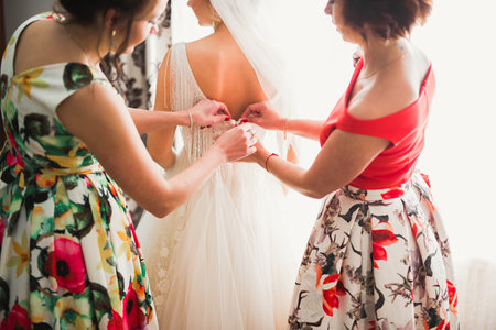 Hands of bridesmaids on bridal dress. Happy marriage and bride at wedding day conceptの写真素材