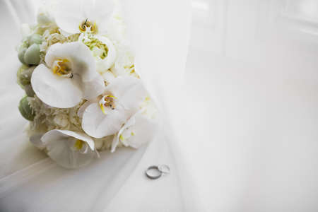 Beautiful toned picture with wedding rings against the background of a bouquet of flowersの写真素材