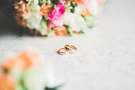 Beautiful toned picture with wedding rings against the background of a bouquet of flowers