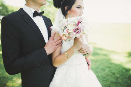Newly married couple running and jumping in park while holding handsの写真素材