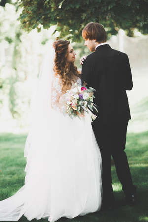 Beautiful romantic wedding couple of newlyweds hugging in park on sunsetの写真素材