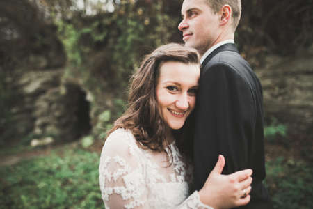 Beautiful young wedding couple is kissing and smiling in the parkの写真素材