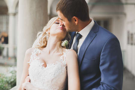 Lovely happy wedding couple, bride with long white dress posing in beautiful cityの写真素材