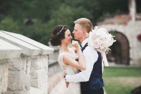 Romantic, fairytale, happy newlywed couple hugging and kissing in a park, trees in backgroundの写真素材