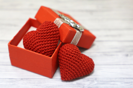 Valentine gift box with red knitted hearts on light wooden table. Love conceptの写真素材