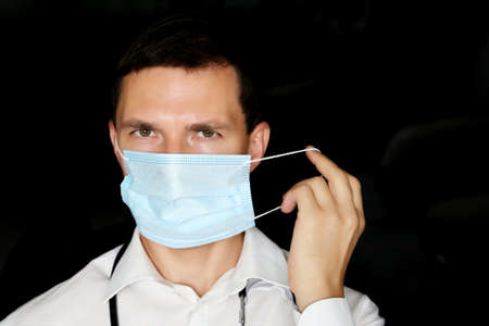 Man removes the disposable medical mask. Tired doctor after hard work, concept of surgery or...