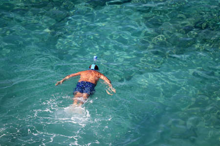 Snorkeling in the sea, beach vacation. Man in mask swim in a clear blue water, top viewの写真素材