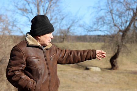 Angered elderly man gestures outdoor. Rural scene, concept of old age, life in village