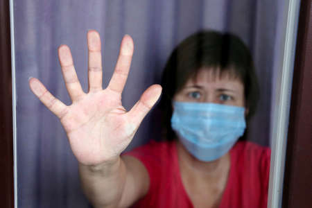 Quarantine during the covid-19 coronavirus epidemic, female palm of hand on the window. Worried...